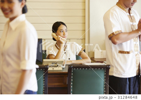 a receptionist is looking outside and answering the phone. a receptionist is looking outside and answering the phone. 31284648