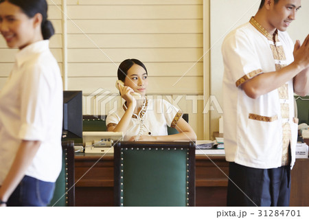 A photo of young receptionist talking on phone at a reception desk. A photo of young receptionist talking on phone at a reception desk. 31284701