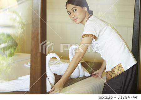 The housekeeper is placing swans made of towels on the bed. 31284744