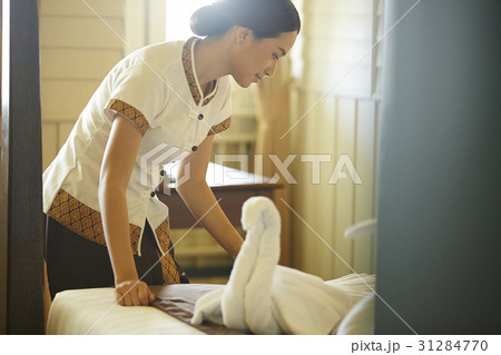 A photo of young housekeeper is making the bed in a room. 31284770