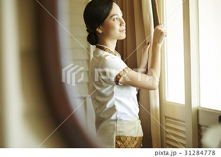 A female staff is adjusting curtains in the hotel room. 31284778