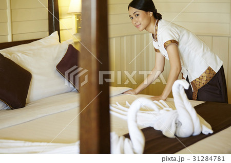 The beautiful maid is arranging the bed in hotel room. 31284781