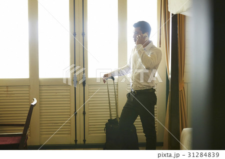 Businessman is holding his suitcase and answering the phone 31284839