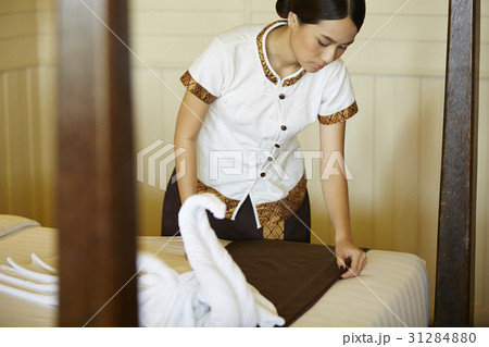 The staff is tidying up bed in hotel room. The staff is tidying up bed in hotel room. 31284880