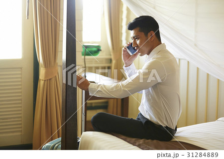 businessman is sitting and talking on phone in a room. businessman is sitting and talking on phone in a room. 31284889