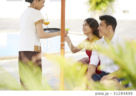 The couple is happy when receiving fruit juice from waitress 31284899