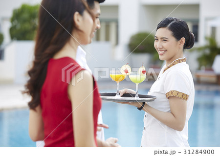 Resort waitress is smiling at the couple on a poolside 31284900