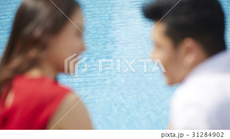 A blurry photo of a couple looking at each other on a poolside 31284902