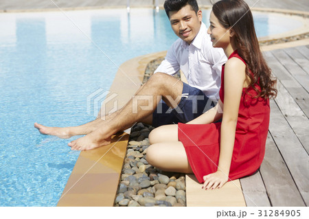 A couple is sitting, enjoying and smiling on a poolside 31284905
