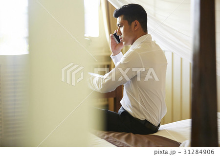 The man is on the bed and talking on his phone 31284906