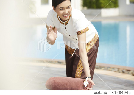 An Asian maid is waving hand to someone when working at resort. 31284949
