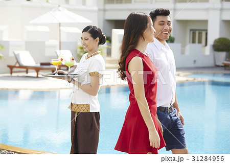 A happy couple is visiting a pool of a resort beside a waitress. A happy couple is visiting a pool of a resort beside a waitress. 31284956