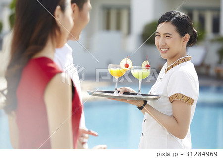 A photo of a happy waitress serving cocktails at pool. 31284969