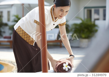 A maid is preparing towel for guest at pool. 31284970