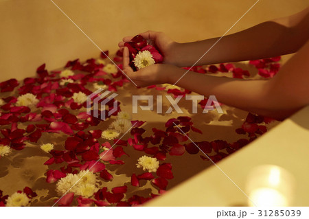 A photo of hands and bathtub with full of petals. 31285039