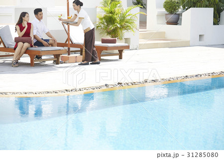 a photo of a couple sitting on a lounger, served drinks a photo of a couple sitting on a lounger, served drinks 31285080