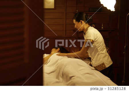 the spa staff is putting towels on a guest lying 31285128