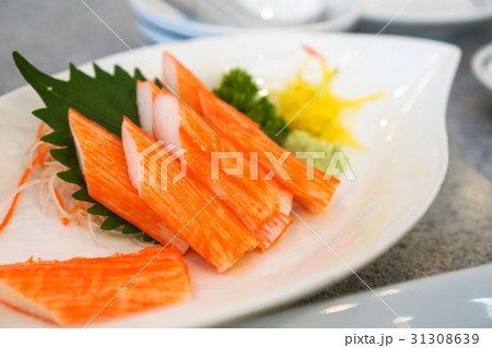 Crab sticks in a white dish placed on a table. 31308639