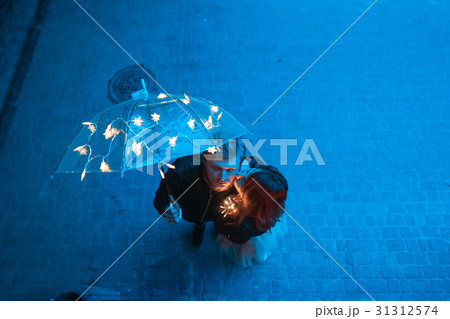 Guy and girl kissing under an umbrella Guy and girl kissing under an umbrella 31312574