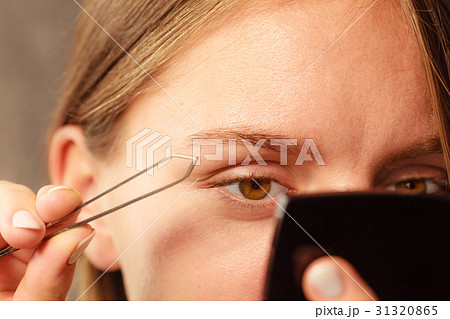 Woman tweezing eyebrows depilating with tweezers 31320865