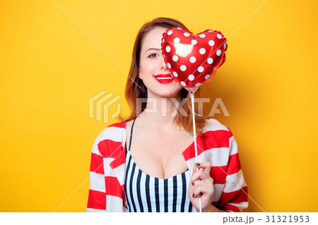 Woman with heart shape toy on yellow background 31321953