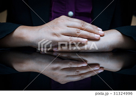 Businesswoman sitting at a desk and clasp her hand Businesswoman sitting at a desk and clasp her hand 31324996