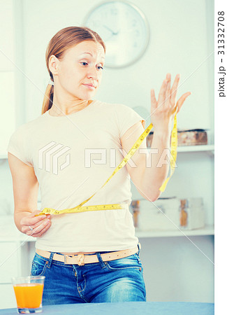 Frustrated woman measuring waist 31332708