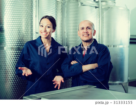 Portrait of cheerful two coworkers standing on wine factory Portrait of cheerful two coworkers standing on wine factory 31333155