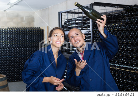 Two adult winery workers holding bottle of wine 31333421