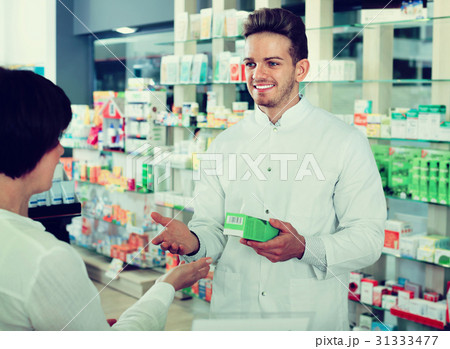 Man pharmacist helping customers in drug store Man pharmacist helping customers in drug store 31333477
