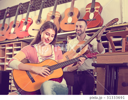 Couple playing guitars in music shop. 31333691