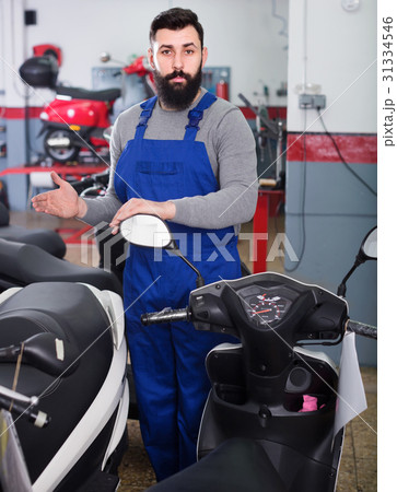 Man worker offering scooters in motorcycle workshop 31334546