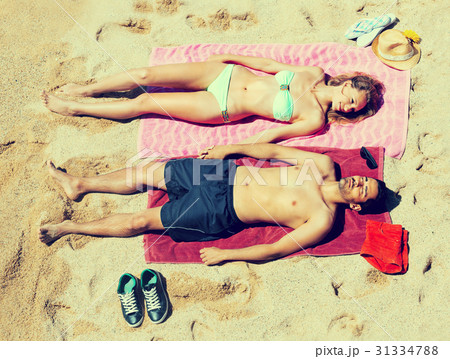 Smiling young lovers sunbathing at sandy beach Smiling young lovers sunbathing at sandy beach 31334788