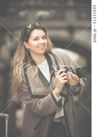 Girl holding camera in hands and photographing in the city 31335003