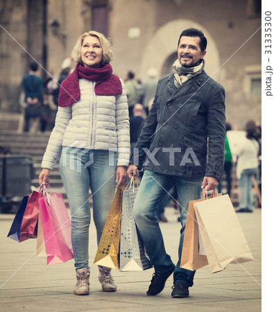elderly couple walking and carrying shopping bags 31335300