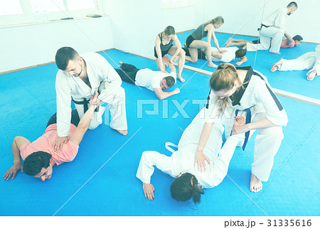trainees sparring in pairs to practice new holds in taekwondo class 31335616