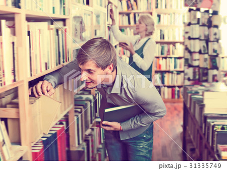Adult laughing man choosing new book from many Adult laughing man choosing new book from many 31335749