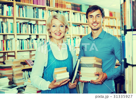 Smiling young man and mature woman holding books Smiling young man and mature woman holding books 31335927