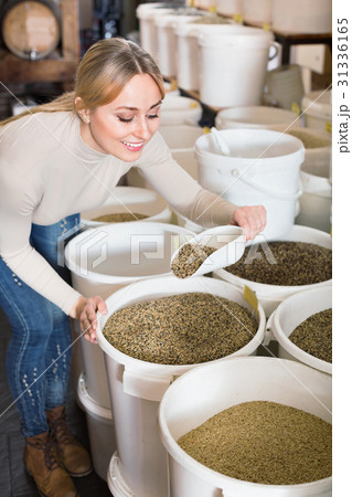 Young female customer taking bird forage with scoop from bucket 31336165