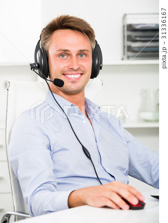 Cheerful man talking on headset at office Cheerful man talking on headset at office 31336167