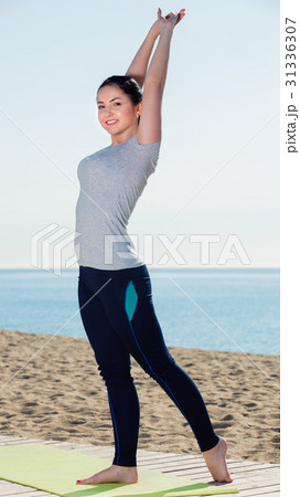 Woman doing exercises on beach by ocean at daytime Woman doing exercises on beach by ocean at daytime 31336307