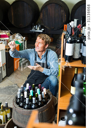 man with glass of wine in wine cellar. 31336668