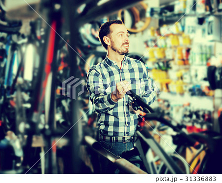 Man considers bicycle handlebar in store 31336883