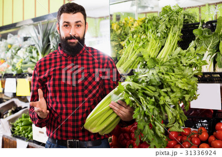 Man seller showing celery in grocery shop Man seller showing celery in grocery shop 31336924