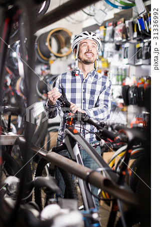 joyous man in helmet chooses for himself sports bike in bicycle shop 31336992