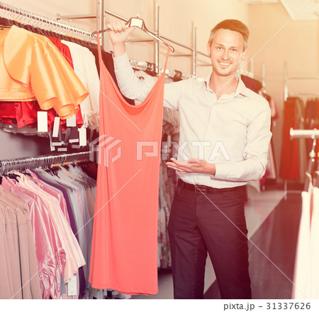 Portrait of young man offering to girlfriend dress variants 31337626