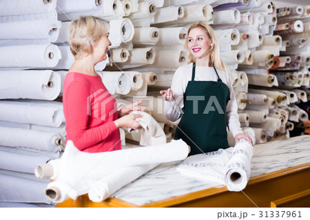 Happy seller offering fabrics to aged woman 31337961