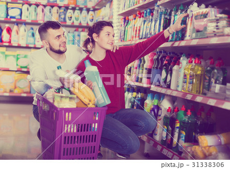 two attentive adult people in good spirits selecting detergents in the store 31338306