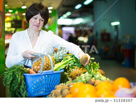 Middle aged woman with basket choosing fruits Middle aged woman with basket choosing fruits 31338307