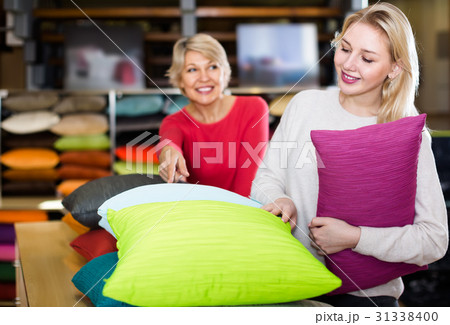 concentrated young and senior female customers looking through pillows in textile shop 31338400